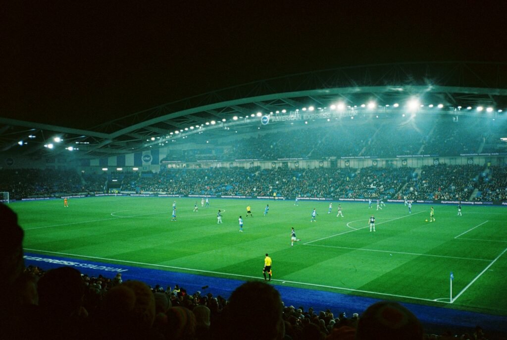 Partida de futebol em estádio à noite